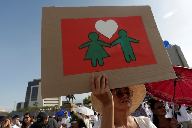 A Florida man holds a cardboard sign as thousands of Catholics and conservatives gather against the legalization of gay marriage.