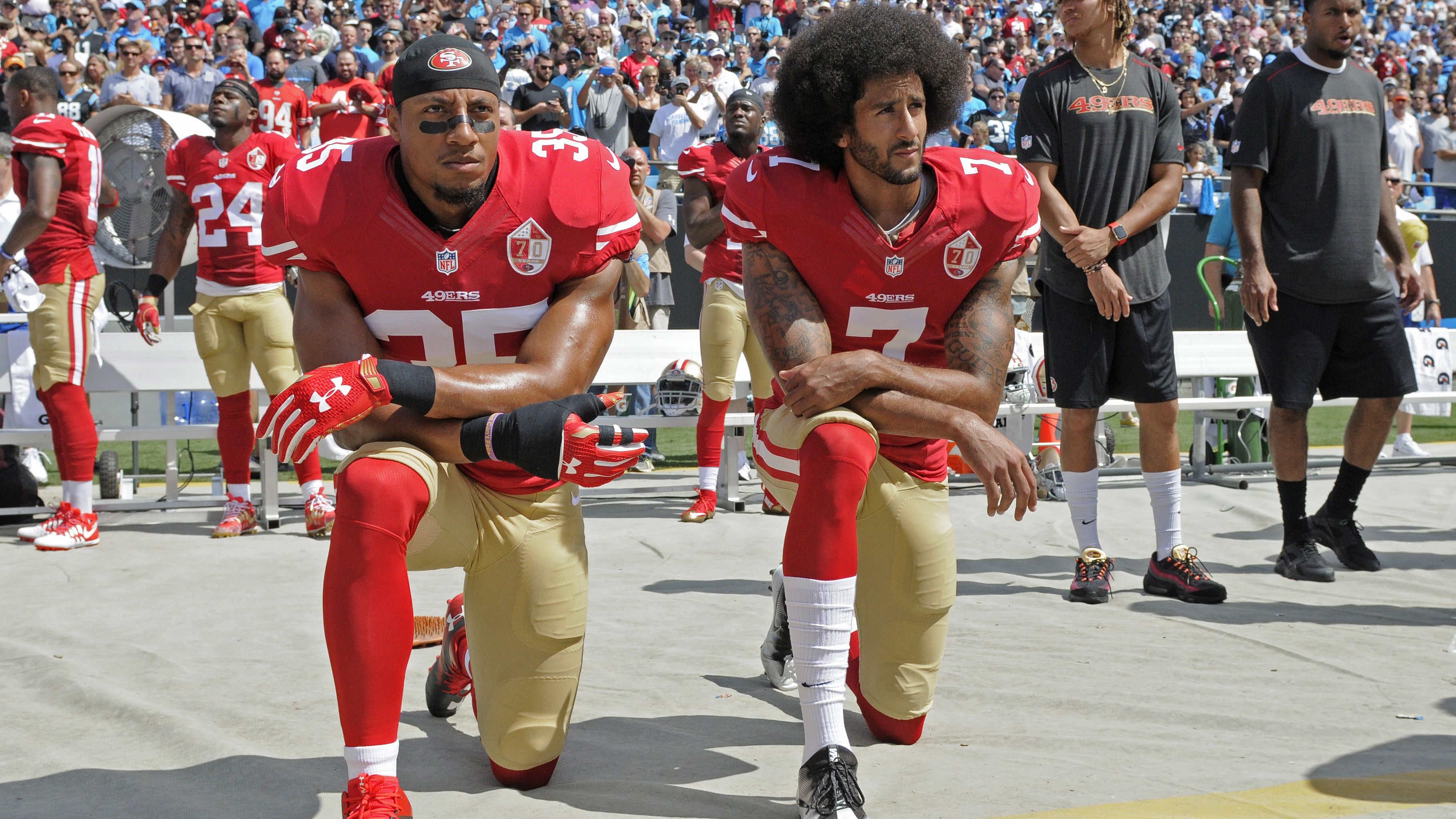 Colin Kaepernick (7) y Eric Reid, de los 49ers de San Francisco, se arrodillan durante la interpretación del himno nacional,antes de un partido de la NFL, frente a los Panthers de Carolina, el domingo 18 de septiembre de 2016 (AP Foto/Mike McCarn)