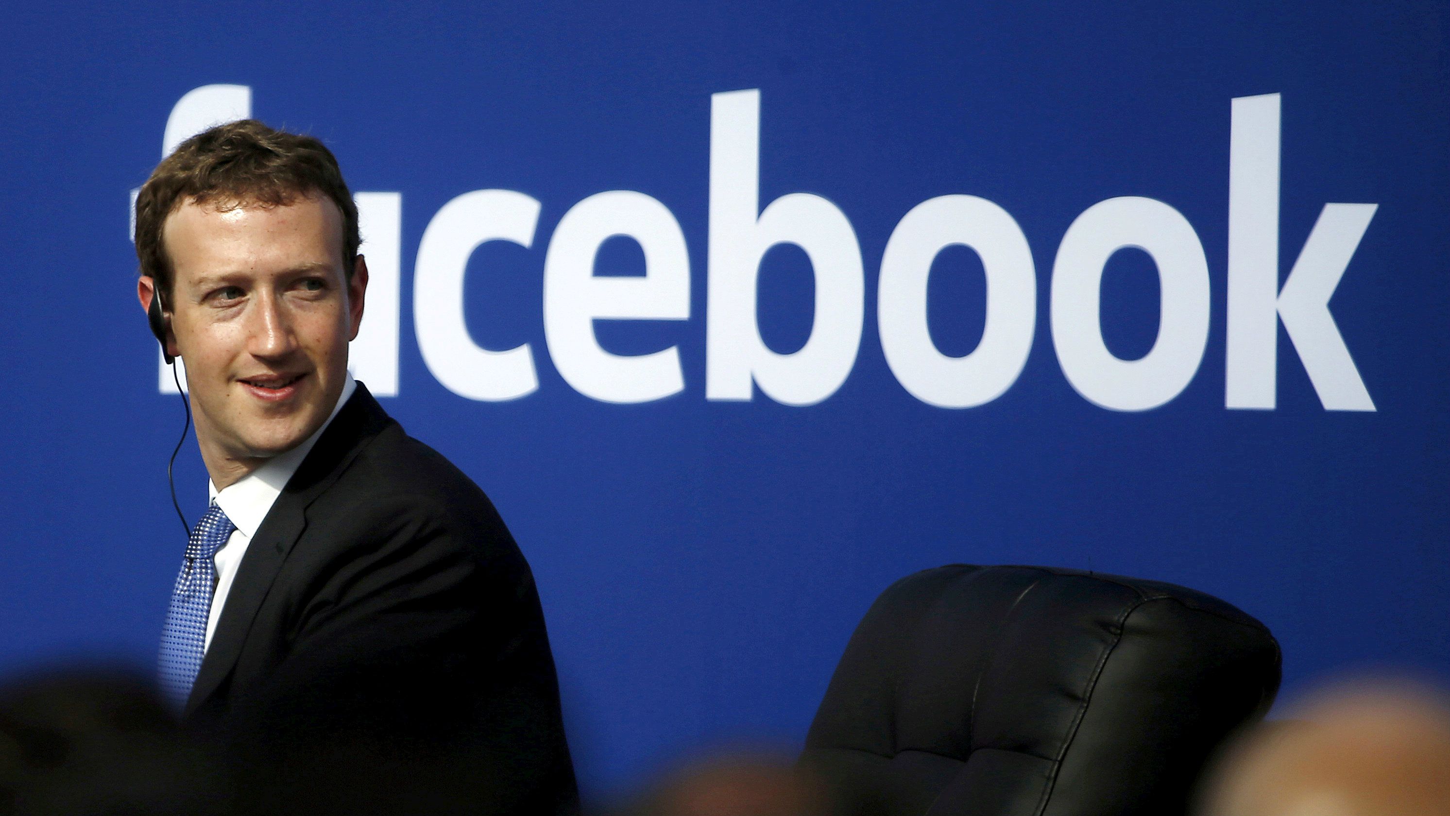 Zuckerberg in front of facebook logo
